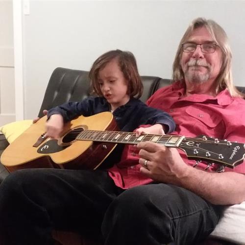 Rick with grandson Gavin playing with Rick's guitar